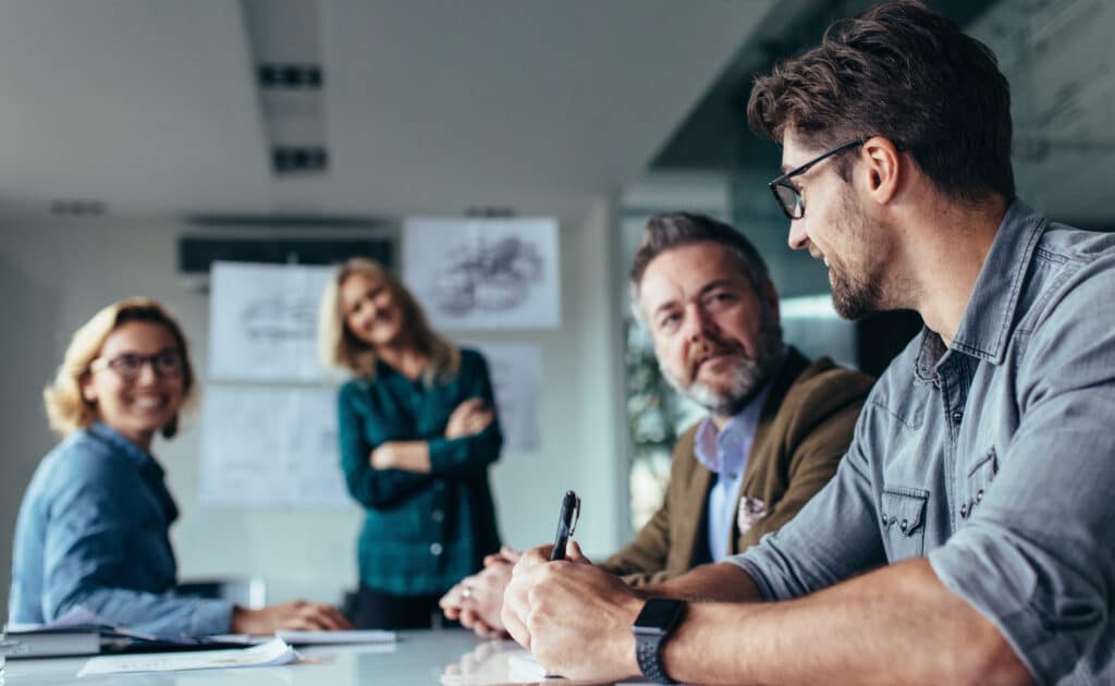 man i fokus som sitter i grupp, de diskuterar och ler, effektivt lärande